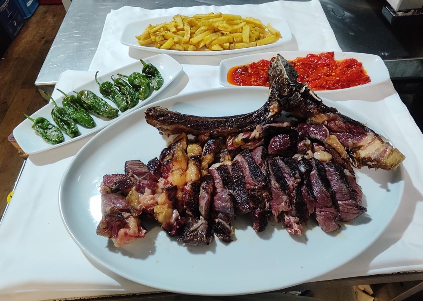 Chuletón recién hecho a la parrilla y cortado, con patatas y pimientos