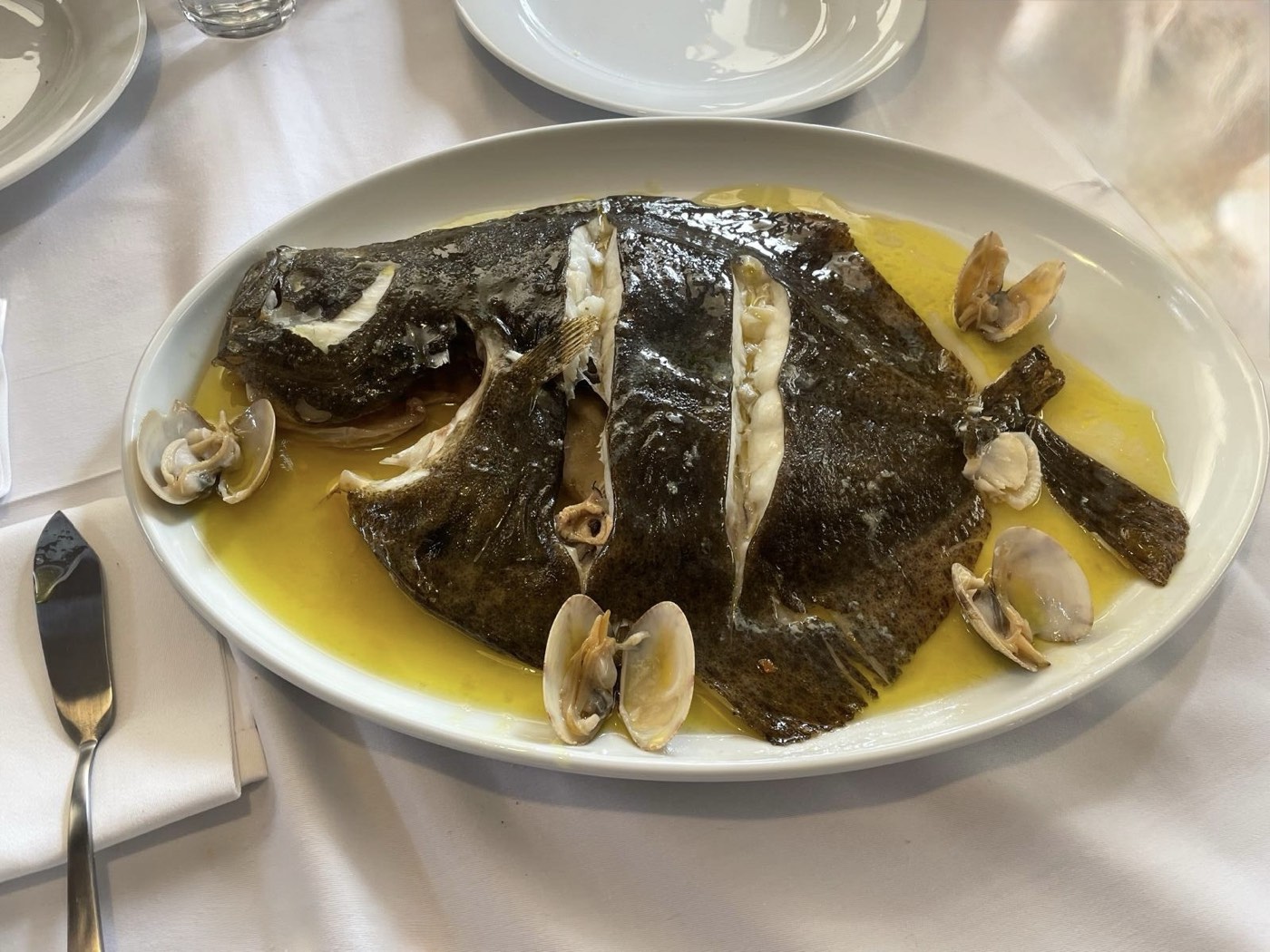 Rodaballo al horno con almejas, servido entero en fuente