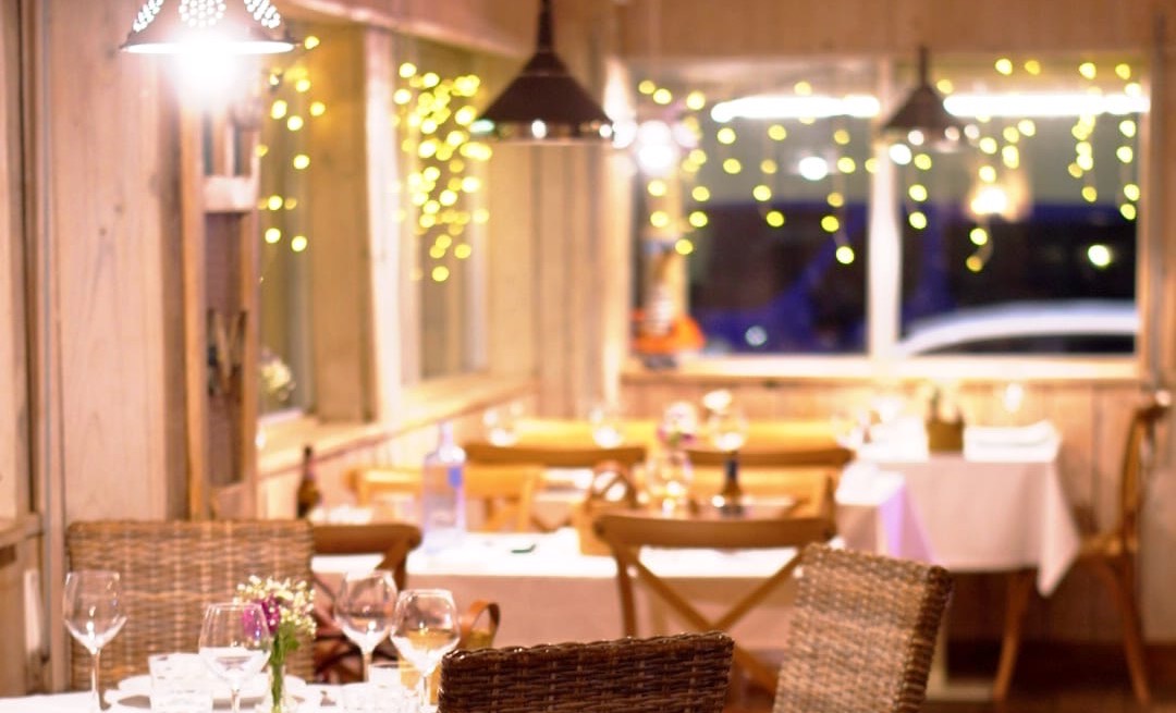 Comedor de La Frisona al anochecer, con las mesas vestidas y guirnaldas de luces en las ventanas